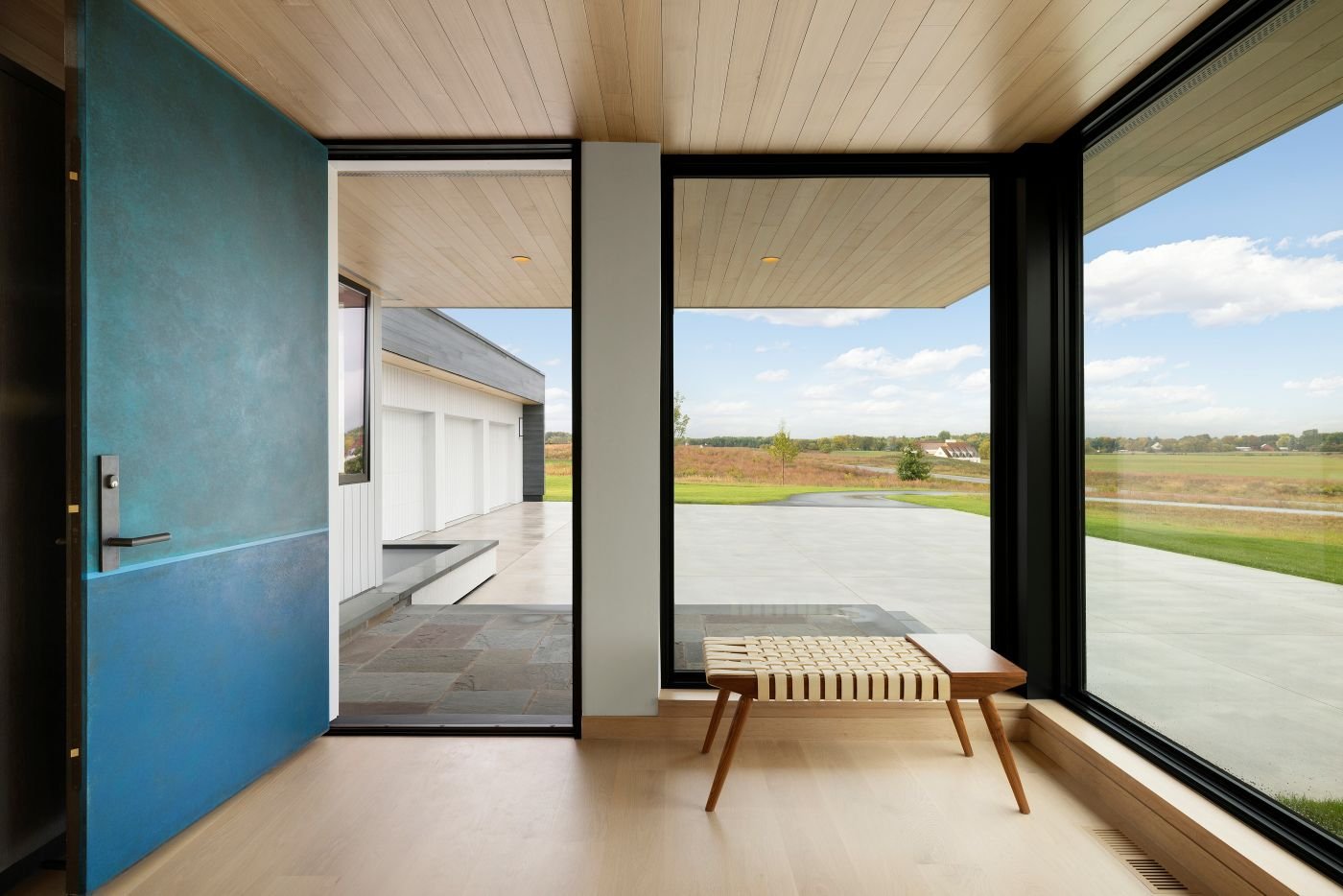 An entryway with floor-to-ceiling windows that wrap around a corner making the most of of the prairie views surrounding the home.