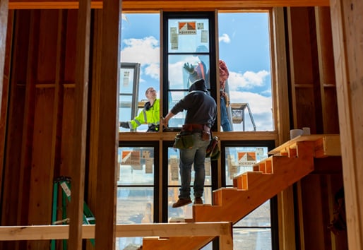 Men installing a wall of windows next to a stair.