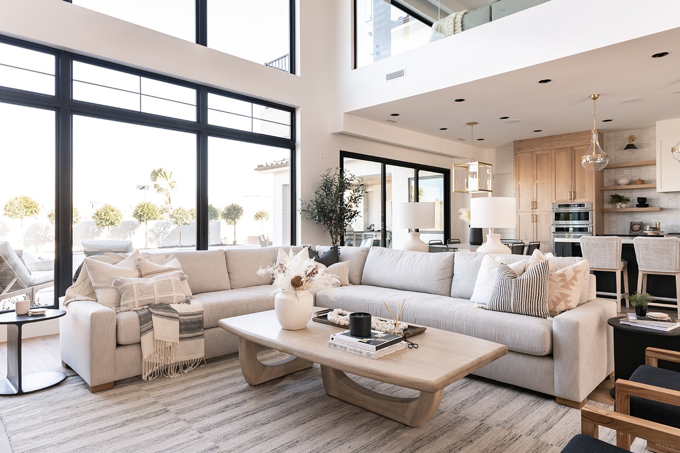 Living room interior with coastal, mediterranean tones and extra-large, black windows. 